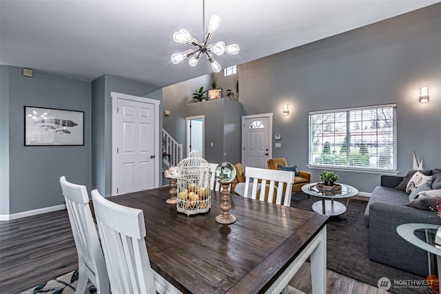 dining room with wood finished floors, a notable chandelier, baseboards, and stairs