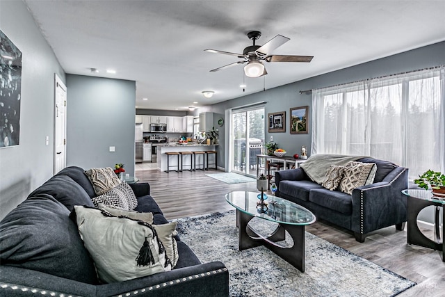 living room featuring light wood finished floors, a ceiling fan, and recessed lighting