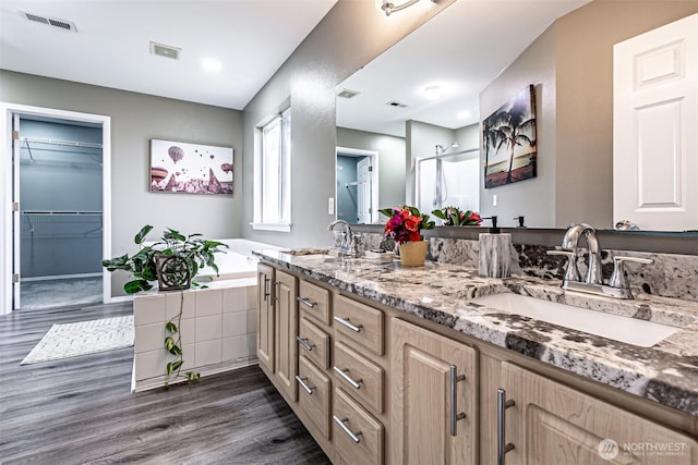 full bathroom with double vanity, wood finished floors, a sink, and visible vents