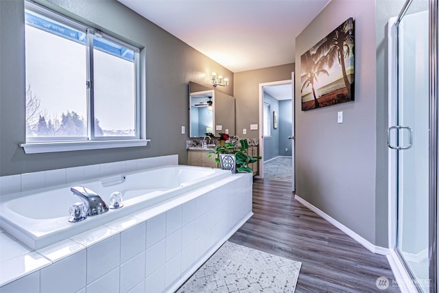 bathroom with a stall shower, wood finished floors, and a bath