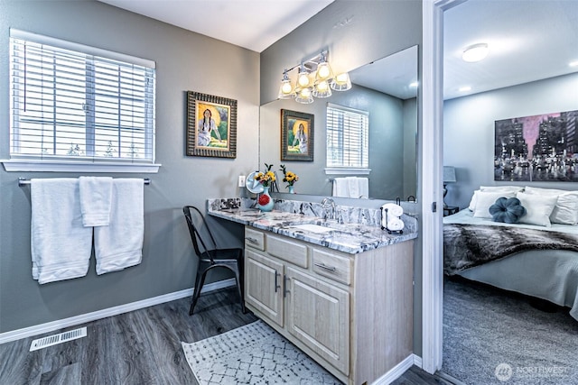 bathroom featuring baseboards, visible vents, wood finished floors, and vanity