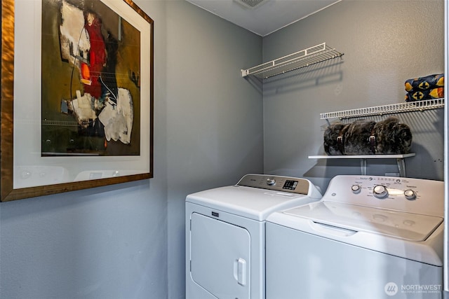 washroom with laundry area, washing machine and dryer, and visible vents