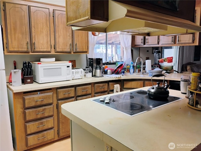 kitchen with range hood, brown cabinets, black electric stovetop, light countertops, and white microwave