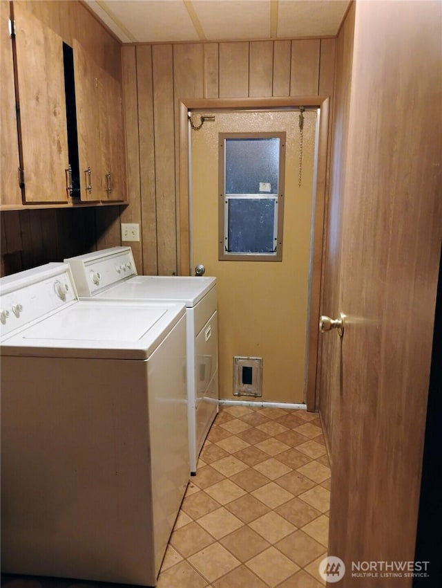 washroom featuring cabinet space, wooden walls, and washer and dryer