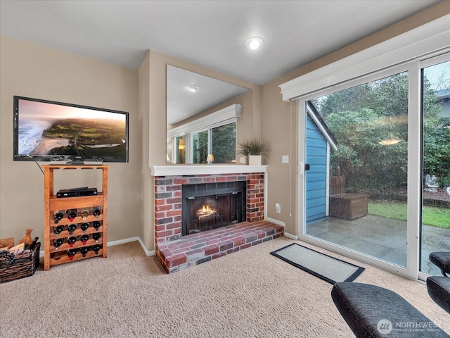 carpeted living area featuring a brick fireplace and baseboards