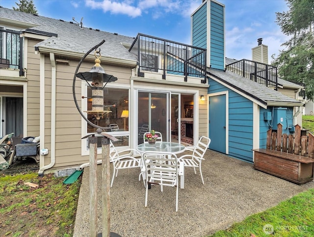 rear view of property with a shingled roof, a patio area, and a balcony