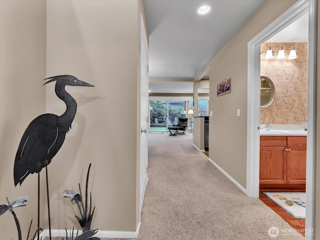 hall featuring carpet floors, recessed lighting, a sink, and baseboards