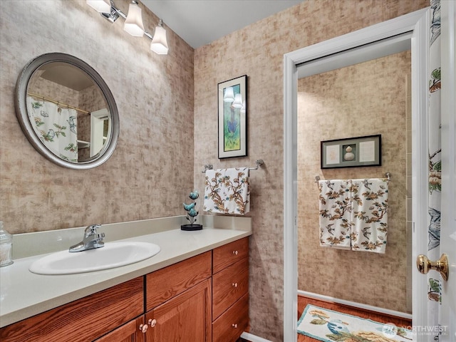 bathroom with vanity and wallpapered walls