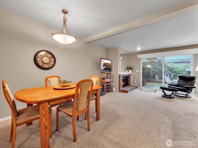 dining room featuring light carpet, a brick fireplace, baseboards, and beamed ceiling