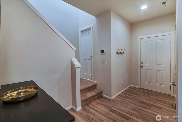 foyer featuring baseboards, visible vents, wood finished floors, stairs, and recessed lighting