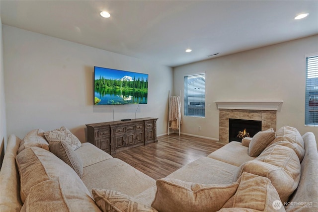 living area with recessed lighting, visible vents, wood finished floors, a tile fireplace, and baseboards