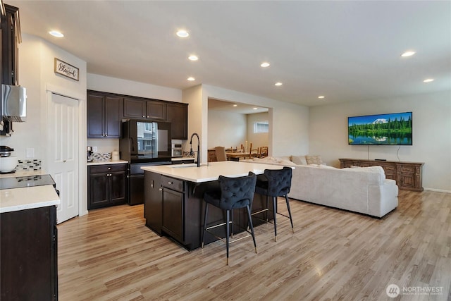 kitchen featuring light wood-style floors, open floor plan, light countertops, and a breakfast bar area