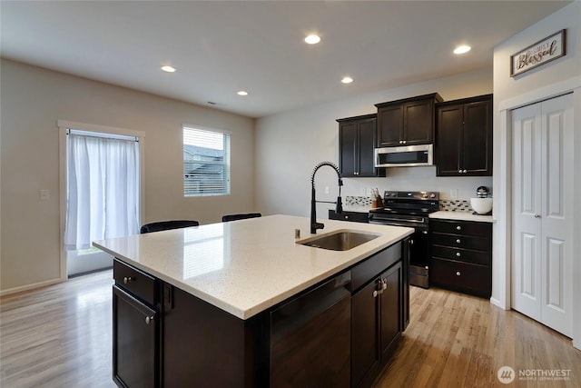 kitchen featuring a kitchen island with sink, light wood-style flooring, recessed lighting, stainless steel appliances, and a sink