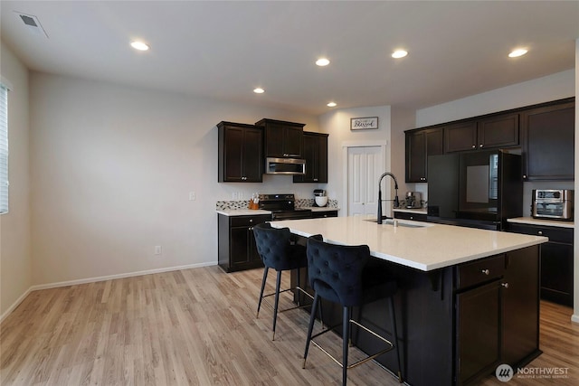 kitchen with stainless steel microwave, fridge, range with electric stovetop, and a kitchen breakfast bar