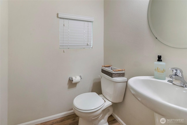 bathroom featuring wood finished floors, a sink, toilet, and baseboards