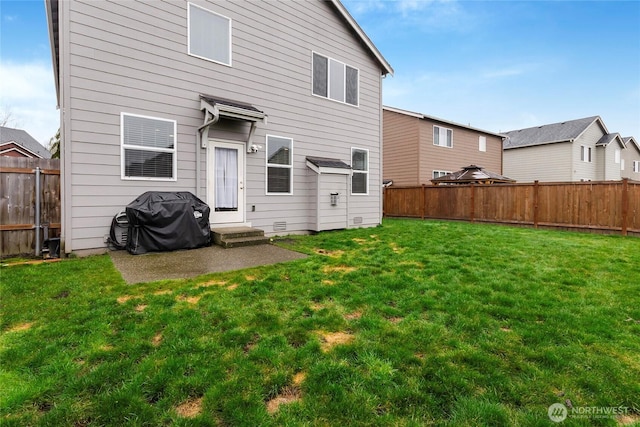 back of property featuring entry steps, a lawn, and a fenced backyard