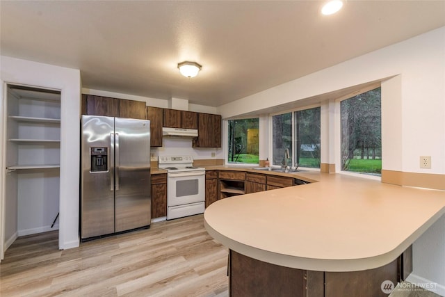 kitchen featuring under cabinet range hood, white range with electric stovetop, stainless steel refrigerator with ice dispenser, and light countertops