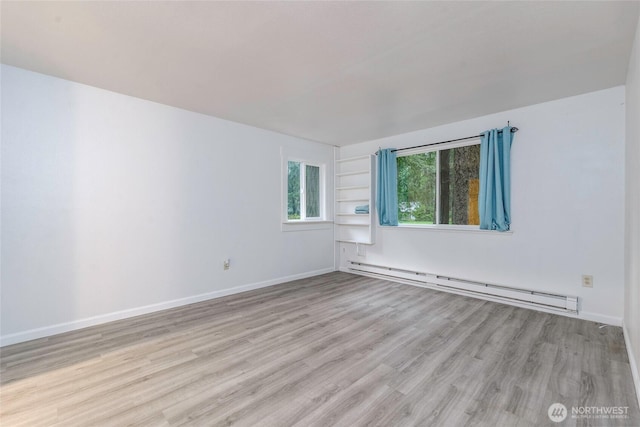 unfurnished room featuring baseboards, baseboard heating, and wood finished floors