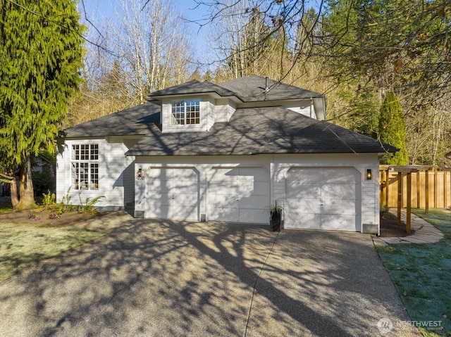 view of front of house featuring concrete driveway, an attached garage, and fence