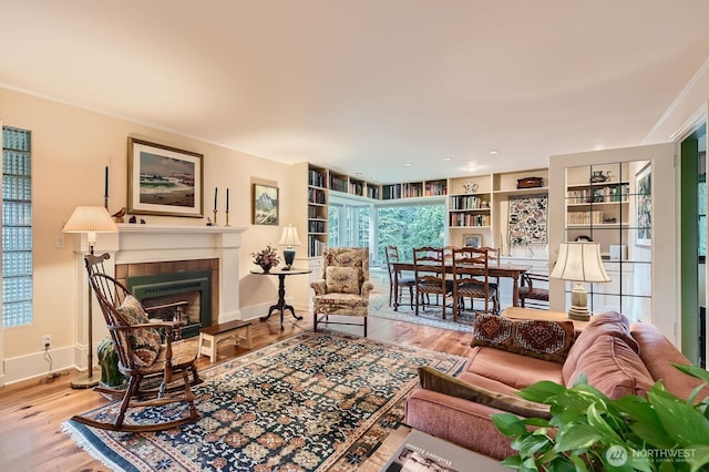 living area featuring built in features, a fireplace, baseboards, and wood finished floors