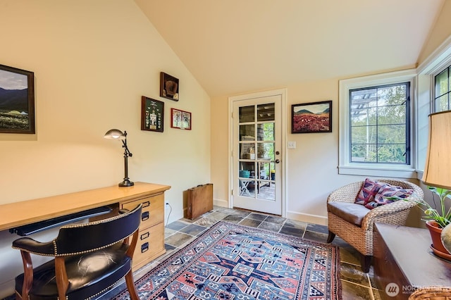 interior space with lofted ceiling, stone finish flooring, built in study area, and baseboards