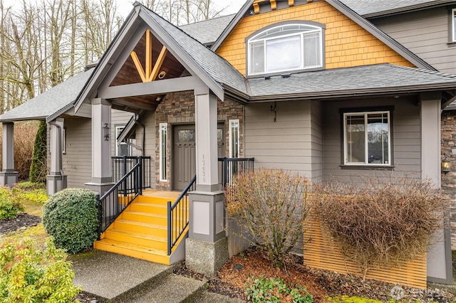 view of exterior entry featuring stone siding and roof with shingles