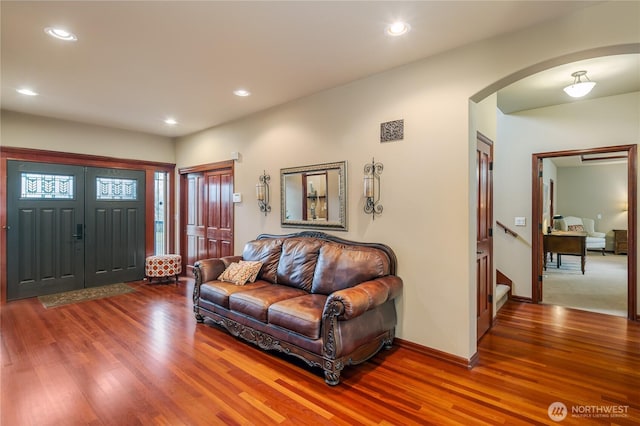 entrance foyer featuring arched walkways, wood finished floors, stairs, and recessed lighting