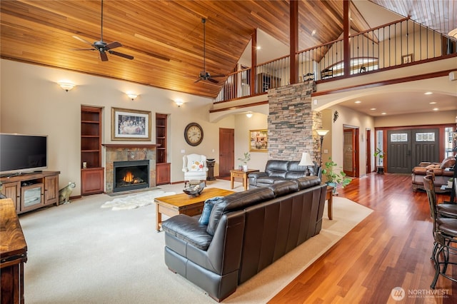 living area with wood ceiling, high vaulted ceiling, a tiled fireplace, and wood finished floors