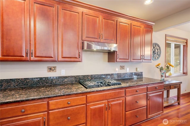 kitchen with black gas stovetop, recessed lighting, under cabinet range hood, wood finished floors, and dark stone countertops