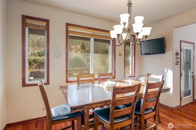 dining area with baseboards, a chandelier, and wood finished floors