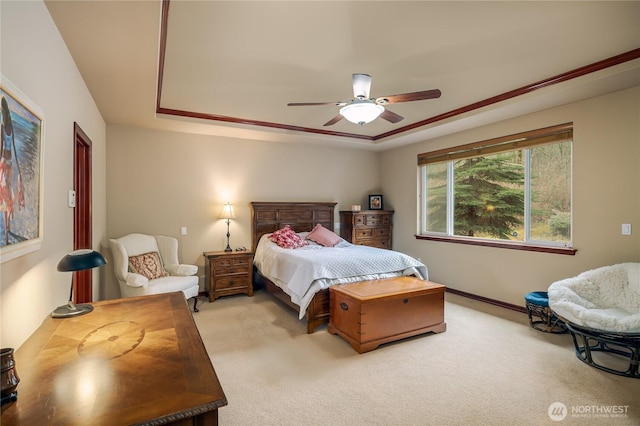 bedroom with a raised ceiling, a ceiling fan, and light colored carpet