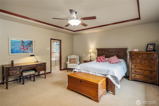 bedroom featuring ensuite bath, a raised ceiling, a ceiling fan, and light colored carpet