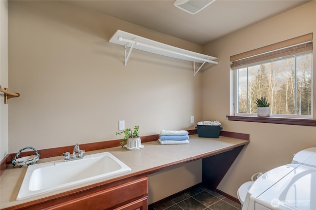 laundry area featuring dark tile patterned floors, independent washer and dryer, a sink, and visible vents