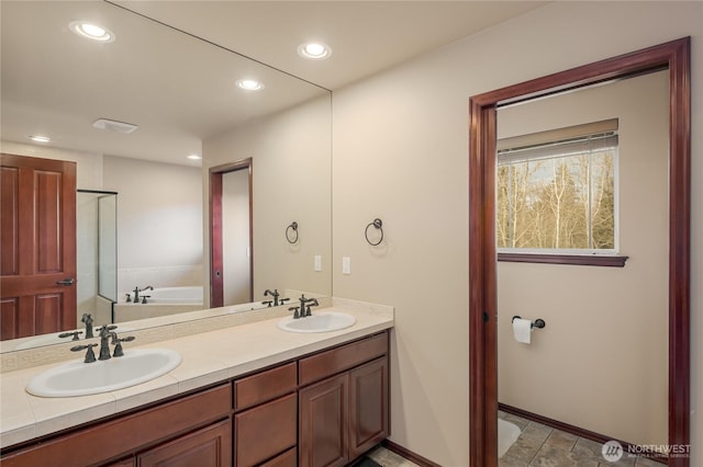 full bath featuring a sink, a bath, and recessed lighting