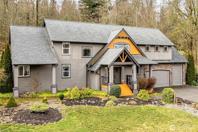 view of front facade with a garage, driveway, a shingled roof, and a front lawn