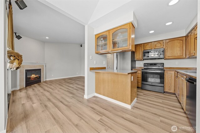 kitchen with open floor plan, appliances with stainless steel finishes, glass insert cabinets, and light wood-style floors