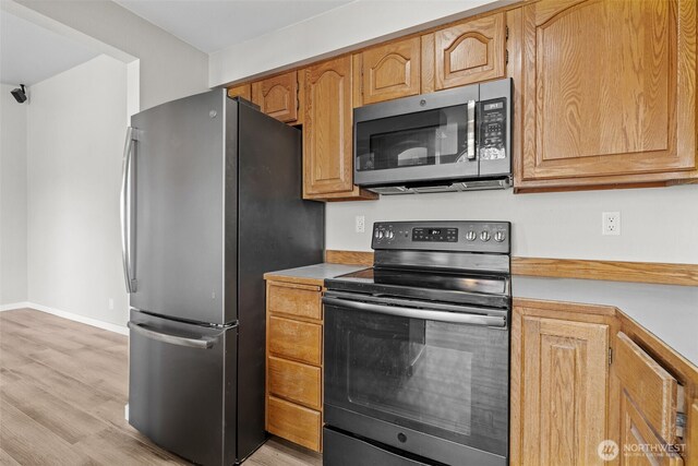 kitchen with baseboards, light countertops, light wood finished floors, and stainless steel appliances