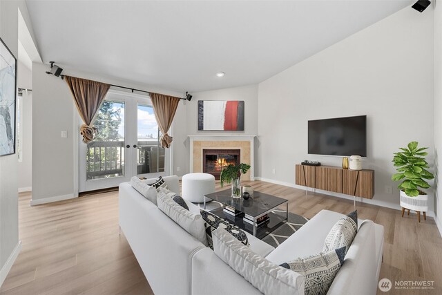 living room featuring baseboards, a high end fireplace, light wood finished floors, and recessed lighting