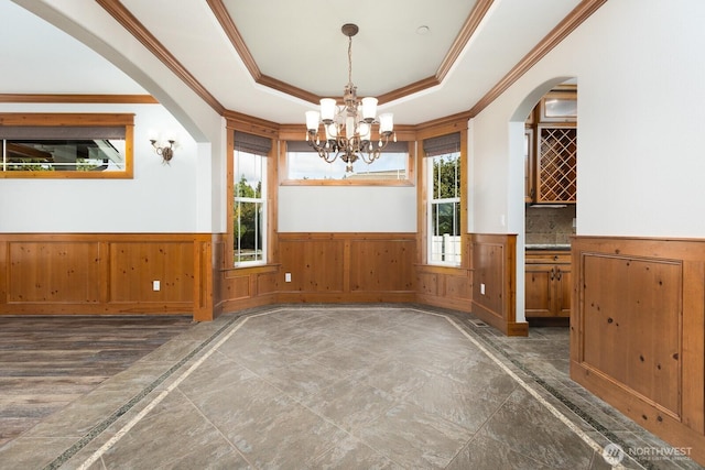 spare room with plenty of natural light, a raised ceiling, and wainscoting