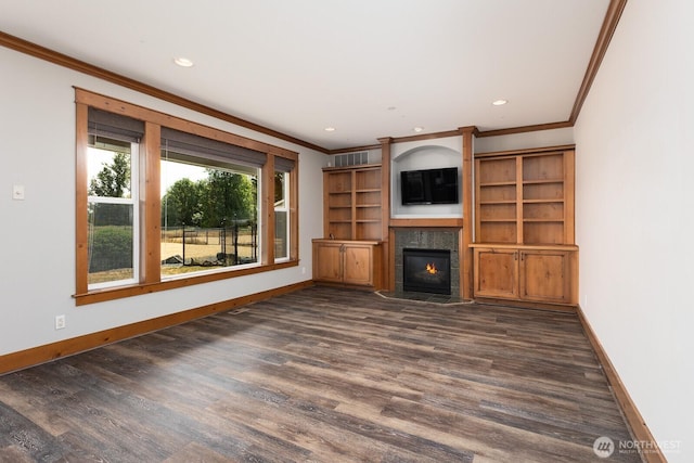 unfurnished living room with a warm lit fireplace, baseboards, dark wood-type flooring, and ornamental molding