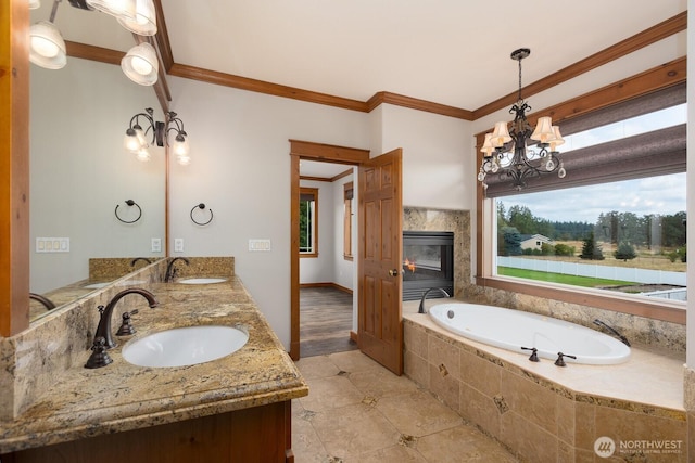 full bath featuring a bath, ornamental molding, a chandelier, and a sink