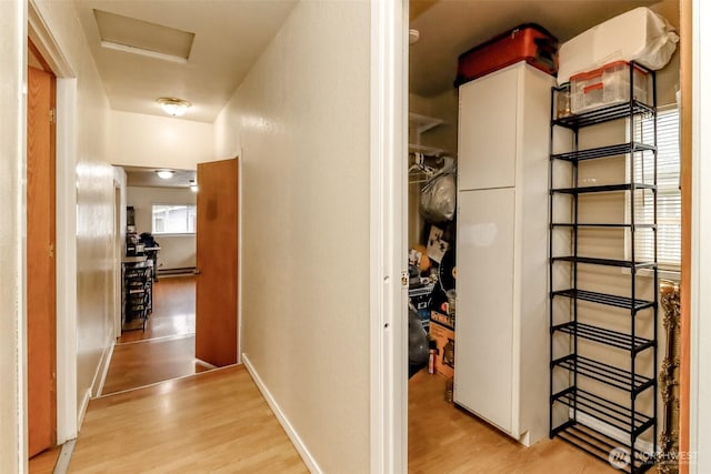 hallway featuring light wood finished floors, attic access, and baseboards