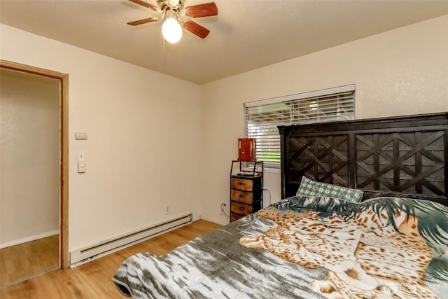 bedroom with baseboard heating, wood finished floors, a ceiling fan, and baseboards