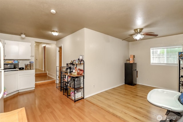 sitting room with a ceiling fan, baseboards, and light wood finished floors