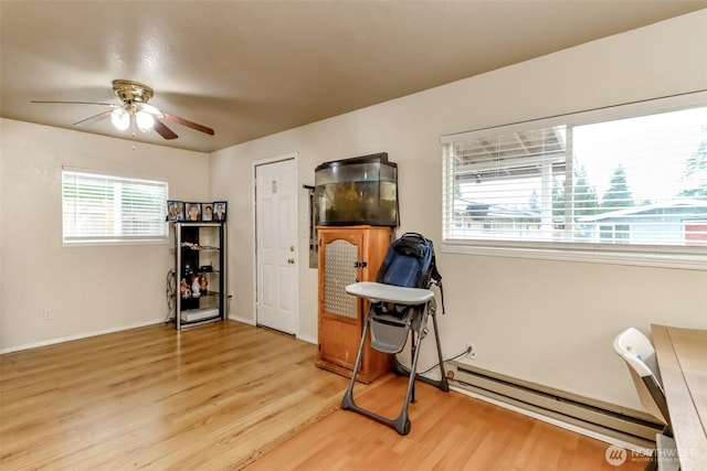 interior space with light wood-type flooring, a baseboard radiator, a ceiling fan, and baseboards