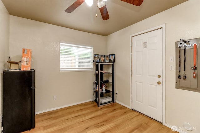 miscellaneous room with baseboards, ceiling fan, light wood-style flooring, and electric panel