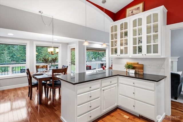 kitchen with vaulted ceiling, dark countertops, and hardwood / wood-style flooring