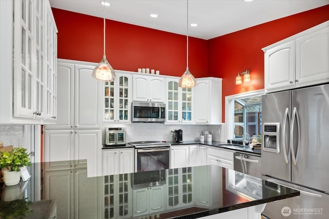 kitchen with white cabinets, decorative backsplash, appliances with stainless steel finishes, pendant lighting, and a sink