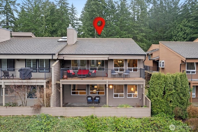 rear view of house with a shingled roof and a chimney