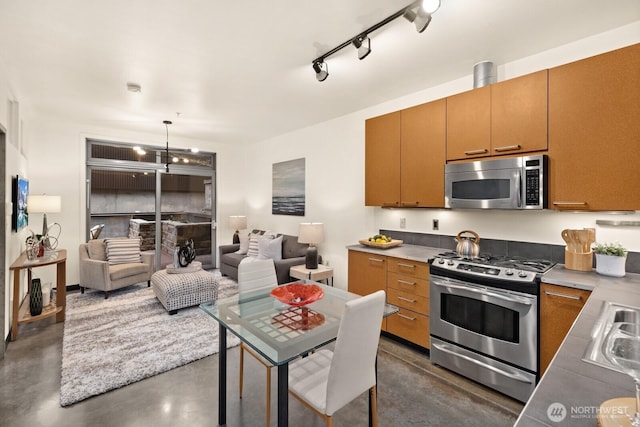 kitchen with open floor plan, decorative light fixtures, stainless steel appliances, concrete floors, and a chandelier